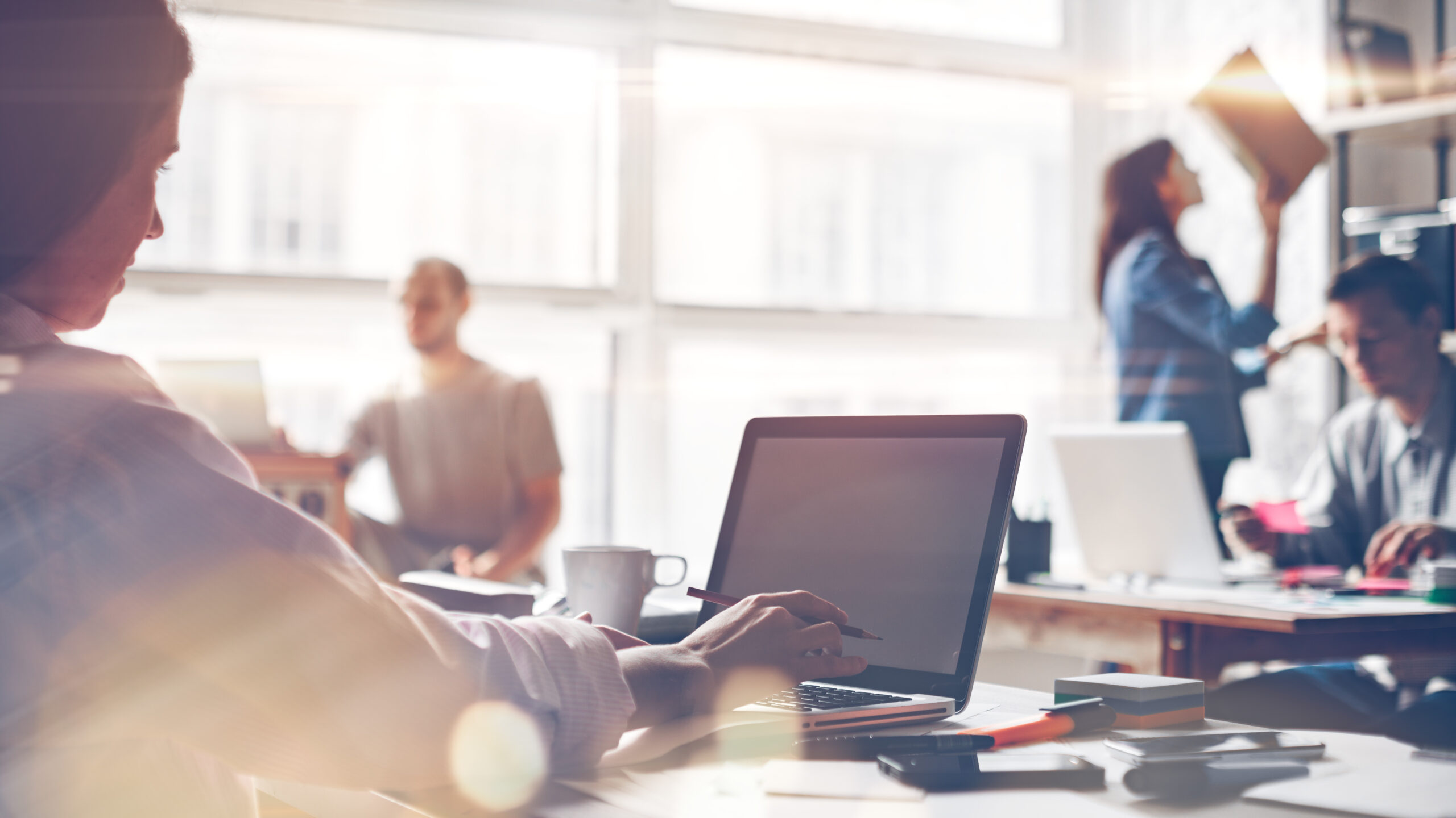 Startup team at work. Big open space office, laptops and paperwork. Business concept. Film effect and lens flare effect, blurry background